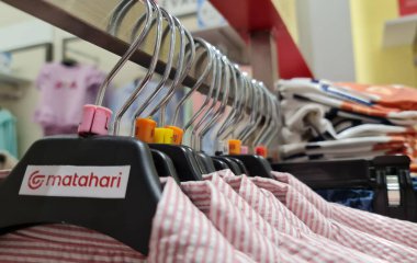 Bekasi, Indonesia on December 20 2023. Rows of hangers with the words Matahari, clothes with red vertical stripes on a white base hanging on the hangers. Matahari is one of cheap malls in Indonesia clipart