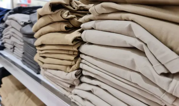 Bir giyim mağazasında bir yığın çocuk giysisi. İndirimli pamuk giysi. Çeşitli renkler arasında gri, turuncu, kahverengi ve diğerleri vardır. Çocukların giymesi için rahat..