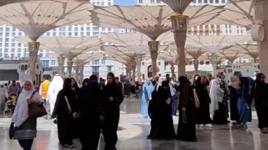 Medine, Suudi Arabistan, 2 Mart 2024. Nabawi Camii 'nin avlusunda yürüyen bir umrah veya hacının bakış açısı. Yürüyen ve ibadet eden cemaati saran görkemli ve güzel şemsiyeleri görebilirsiniz..