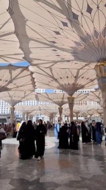 Medine, Suudi Arabistan, 2 Mart 2024. Nabawi Camii 'nin avlusunda yürüyen bir umrah veya hacının bakış açısı. Yürüyen ve ibadet eden cemaati saran görkemli ve güzel şemsiyeleri görebilirsiniz..