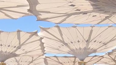 Medine, Suudi Arabistan, 2 Mart 2024. Nabawi Camii 'nin avlusunda yürüyen bir umrah veya hacının bakış açısı. Yürüyen ve ibadet eden cemaati saran görkemli ve güzel şemsiyeleri görebilirsiniz..