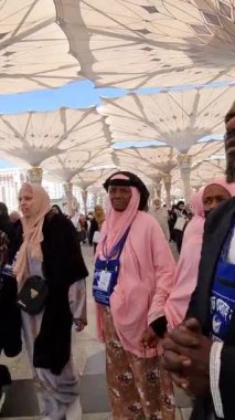 Medine, Suudi Arabistan, 2 Mart 2024. Nabawi Camii 'nin avlusunda yürüyen bir umrah veya hacının bakış açısı. Yürüyen ve ibadet eden cemaati saran görkemli ve güzel şemsiyeleri görebilirsiniz..