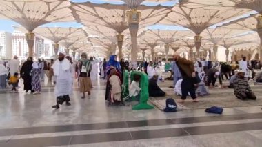 Medine, Suudi Arabistan, 2 Mart 2024. Nabawi Camii 'nin avlusunda yürüyen bir umrah veya hacının bakış açısı. Yürüyen ve ibadet eden cemaati saran görkemli ve güzel şemsiyeleri görebilirsiniz..