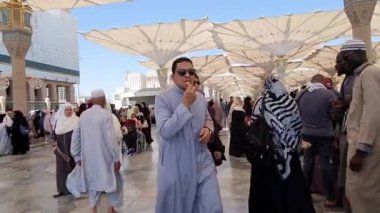 Medine, Suudi Arabistan, 2 Mart 2024. Nabawi Camii 'nin avlusunda yürüyen bir umrah veya hacının bakış açısı. Yürüyen ve ibadet eden cemaati saran görkemli ve güzel şemsiyeleri görebilirsiniz..