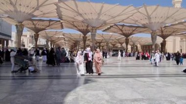 Medine, Suudi Arabistan, 2 Mart 2024. Nabawi Camii 'nin avlusunda yürüyen bir umrah veya hacının bakış açısı. Yürüyen ve ibadet eden cemaati saran görkemli ve güzel şemsiyeleri görebilirsiniz..
