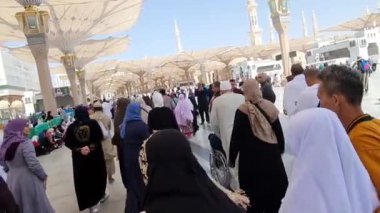 Medine, Suudi Arabistan, 2 Mart 2024. Nabawi Camii 'nin avlusunda yürüyen bir umrah veya hacının bakış açısı. Yürüyen ve ibadet eden cemaati saran görkemli ve güzel şemsiyeleri görebilirsiniz..