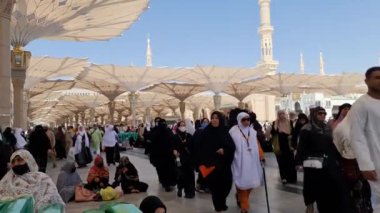 Medine, Suudi Arabistan, 2 Mart 2024. Nabawi Camii 'nin avlusunda yürüyen bir umrah veya hacının bakış açısı. Yürüyen ve ibadet eden cemaati saran görkemli ve güzel şemsiyeleri görebilirsiniz..