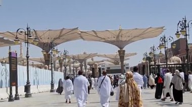 Medine, Suudi Arabistan, 2 Mart 2024. Nabawi Camii 'nin avlusunda yürüyen bir umrah veya hacının bakış açısı. Yürüyen ve ibadet eden cemaati saran görkemli ve güzel şemsiyeleri görebilirsiniz..
