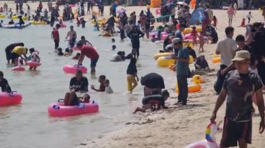 Jepara, 28 Nisan 2024. Bandengan veya Tirta Samudra sahillerini ziyaret edenler sahilde tatilin tadını çıkarıyorlar, bazıları yüzüyor, şamandıralarla oynuyor ve sahilde başka aktiviteler yapıyorlar..