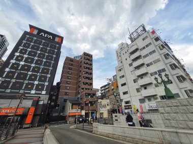 Osaka, Japonya 05 Ekim 2023. Tokyo caddesinin büyüleyici manzarası, parçalı bulutlu bir gökyüzü altında modern binalar sergileniyor. Sahnede zıt mimari tarzlar ve canlı ama sakin bir atmosfer yer alıyor..