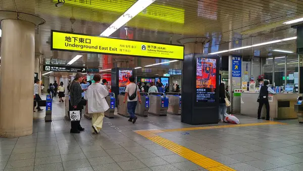 Tokyo, Japonya 01 Ekim 2023. Modern bir Japon metro istasyonunun doğu çıkışında. Yolcular bilet kapılarını kullanıyor ve dijital tabelalarda reklamlar ve bilgiler yer alıyor. Genel ayarı temiz ve iyi aydınlatılmış, tipik bir alçak gönüllülük örneği.