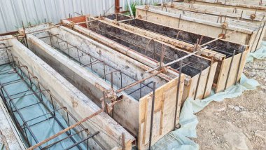 Beton temel inşaatı için beton çubuklu ahşap formlar hazır ve inşaata hazır. İnşaat alanının ilerlemesini gösteriyor..