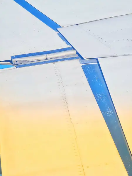 Uçuş sırasında bir uçak kanadının yakın plan görüntüsü havacılık ve seyahat temaları için mükemmel olan yapıyı ve mavi gökyüzünü gözler önüne serer..