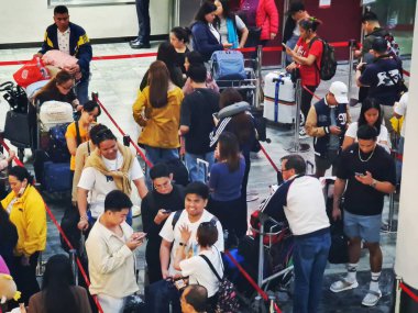 Taipa, Macau 13 Kasım 2024. Havaalanının hareketli kalkış salonu, bagaj arabaları ve telefonlarıyla seyahat eden yolcularla dolu. Sahne yoğun, ama sakin, beklenti içinde..