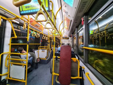 Taipa, Macau 13 Kasım 2024. Sakin bir akşam otobüsü yolculuğu. Sarı korkuluklar ve yumuşak ışıklandırma, çoğunlukla boş olan iç kısımları aydınlatarak, barışçıl bir atmosfer yaratıyor. Birkaç yolcu yerlerinde..