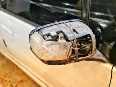 Subang, Endonezya 30 Ekim 2024. Kırık bir arabanın yan aynasının yakın plan görüntüsü iple tutturulmuş, bu da geçici bir onarım durumu olduğunu gösteriyor. Bu görüntü araba tamiri ve bakım teması için kullanılabilir..