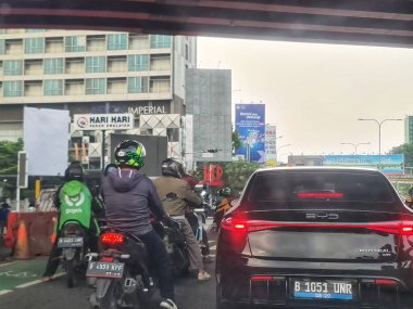 Bekasi, Endonezya 1 Mayıs 2025. Motosikletli şehir trafiği ve trafik ışıklarında duran ya da trafik sıkışıklığında bekleyen bir araba, kentsel yaşam tarzı fotoğrafları için mükemmel..
