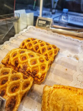 Bekasi, Endonezya 21 Nisan 2025. Altın kare hamur işlerinin yakın plan çekimlerinde beyaz kağıt tepside dekoratif bir kafes kabuğu sergilenir. Bu yemek blogları ve pastane menüleri için mükemmeldir..