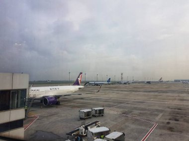 Taipa, Macau 6 Kasım 2024 'te. Air Macau 'da. Bulutlu bir gökyüzünün altında sessiz bir havaalanı sahnesi sergileniyor. Asfalta birkaç uçak park etmiş durumda, yük arabaları yakında bekliyor, sakin ama endüstriyel bir atmosfer yaratıyorlar..