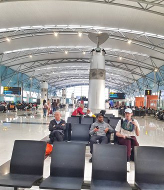 Cengkareng, Endonezya 6 Kasım 2024. Doğal ışıkla yıkanan geniş bir havaalanı bekleme alanında, modern mimari ve uçuşlarını sabırla bekleyen çok sayıda yolcu bulunuyor. Sakin ama beklenen bir ruh hali hakim..