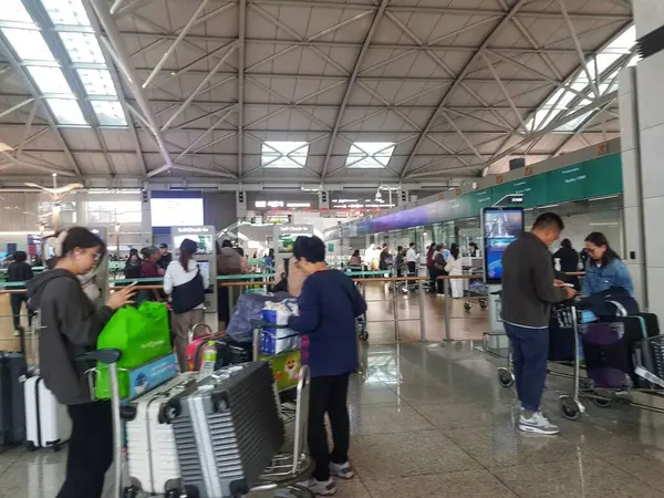 Seul, Güney Kore, 13 Kasım 2024. Incheon Uluslararası Havaalanı. Yoğun havaalanı sahnesi, bavulları ve bavulları olan gezginler giriş sırasında bekliyor. Parlak, modern terminal hareketli ama düzenli bir atmosfer yaratıyor..