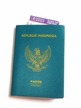 Macau, Çin 14 Kasım 2024. Altından bir Garuda amblemi olan deniz mavisi bir Endonezya pasaportu beyaz bir arka planda duruyor. Tepeden bakan bir biniş kartı. Yolculuk için hazır!