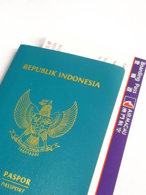 Macau, Çin 14 Kasım 2024. Bir Endonezya pasaportu Air Macau uçuş kartının tepesinde duruyor, önümüzde heyecanlı bir yolculuk olduğunu ima ediyor. Deniz mavisi pasaportunun altın amblemi mor biniş kartına karşı çok güzel bir tezat oluşturuyor.