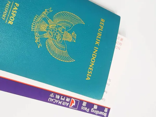 Macau, Çin 14 Kasım 2024. Garuda amblemi taşıyan Endonezya pasaportunun yakın plan görüntüsü Air Macau uçuş kartının tepesinde duruyor. Teal, altın ve mor renkler yolculuğa hazır bir ruh hali yaratır..