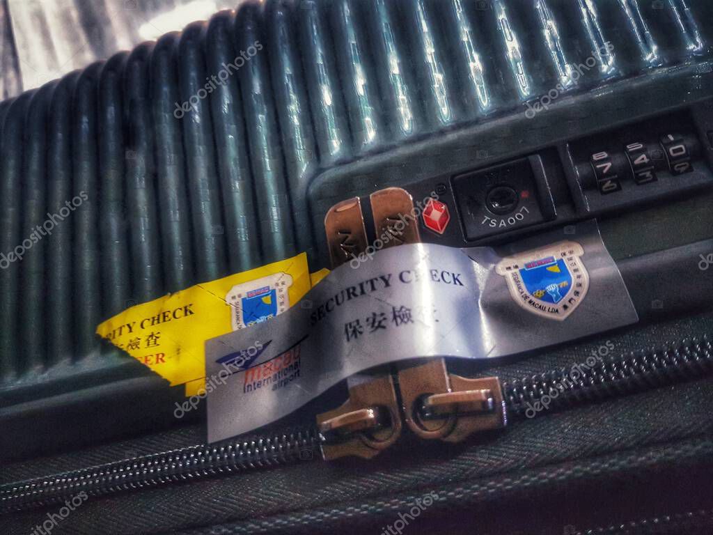 Macau, China on 14 Nov 2024. A textured green suitcase's combination lock and security labels are featured in this close-up shot, evoking a sense of travel and security.
