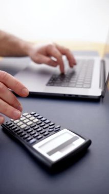 Bütçe planlayan ve mali işleri yöneten bir adam. Bir dizüstü bilgisayar ve hesap makinesi kullanmak hesaplamalar ve maliyet analizine ciddi bir yaklaşımı vurgular. Finansal günlükler ve danışmanlık materyalleri kavramı.