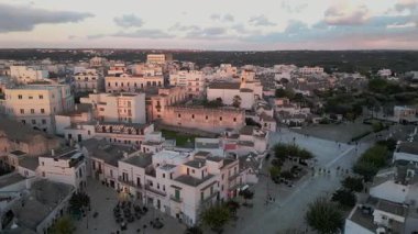 Alberobello 'nun merkezinden uçuyor. Şehir sadece Truli evlerinin muhteşem mimarisi ile değil, aynı zamanda İtalya 'nın gerçek mimarisi ile de ünlüdür. Batan güneşin altında kiremitli çatıları olan beyaz evler.