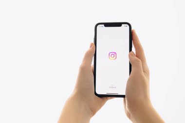 Zaporizhia, Ukrayna - 10 Ocak 2025: Bir kadın evde iş için mobil bir uygulama kullanırken ekranda Instagram uygulama logosu olan bir iPhone tutuyor. beyaz arkaplan