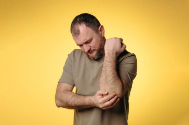 Adamın dirsek ağrısı var. Uzun süreli bilgisayar çalışmalarının olumsuz etkisi, kötü duruş, rahatsız edici iş yeri. Eklem ağrısı ve sağlık sorunlarını önlemek için rahat çalışma alanı kavramı