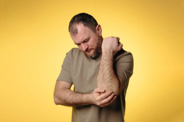 Adamın dirsek ağrısı var. Uzun süreli bilgisayar çalışmalarının olumsuz etkisi, kötü duruş, rahatsız edici iş yeri. Eklem ağrısı ve sağlık sorunlarını önlemek için rahat çalışma alanı kavramı