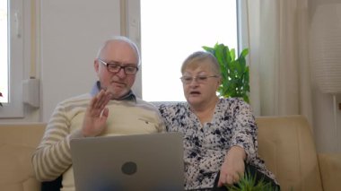 Büyükanne büyükbaba dizüstü bilgisayarın önünde oturuyor ve torunlarıyla video bağlantısı kuruyor. Gülümsüyorlar, hareket ediyorlar, haberleri paylaşıyorlar. Teknoloji aile ilişkilerini sürdürür. Yüksek kalite 4k