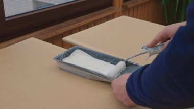 Bir adam, bir ressam, bir marangoz, bir işçi bir tahta boyuyor. Erkek eller ahşap bir tahtanın üzerinde rulo boyayla boyarlar. Ev ve profesyonel onarım teması, inşaat. Yüksek kalite 4k görüntü