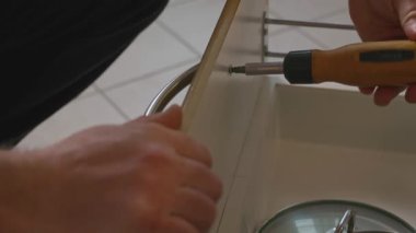 Adamın biri tornavidayla kapı kolunu söküyor. Mobilyaları yakın plan sökme işlemi. Tadilat ya da boyama için hazırlık. Yüksek kalite 4k görüntü