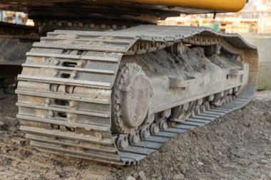 Güneş ışığında sarı bir kazıcıda kirli pist ve silindirleri kapatın. Yüksek kalite fotoğraf