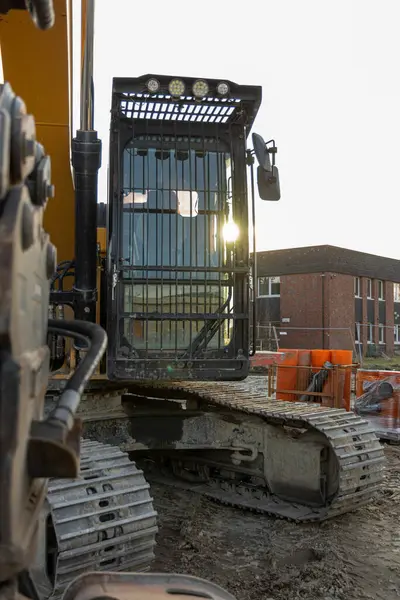 Mavi gökyüzü ve günbatımının arka planına yakın bir inşaat alanında kazıcı. Konut inşaatı için şehir manzarası. Ağır ekipmanlar inşaat sürecini hızlandırır. Yüksek