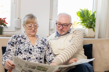 Beyaz, yaşlı bir adam, gri sakallı yaşlı bir dede, karı koca, oturma odasındaki rahat koltukta oturup günlük gazetelerde komik haberler okuyor. Yüksek kalite fotoğraf
