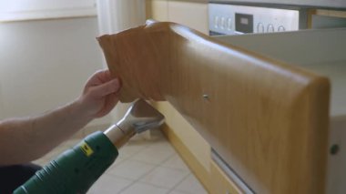 Bir adam eski kaplamaları ahşap bir kapıdan ısı tabancasıyla çıkarır. Yüksek kalite 4K görüntü. Yüksek kalite 4k görüntü