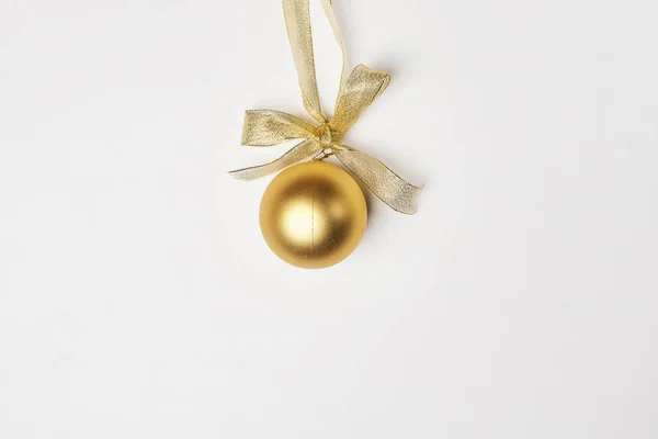 白色背景上的一个金色圣诞球 上面有一条金色的带子 顶上挂着一个弓 — 图库照片