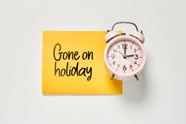 Sarı bir kağıt parçasının üstündeki çalar saat. Bugün siyah mürekkeple yazılmış kelime gitmiş.