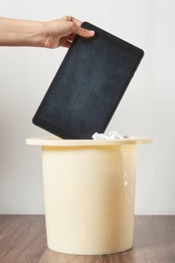 Birisi nasıl kullanıldığını göstermek için kapağı açık bir çöp kutusunda ipad tutuyor.
