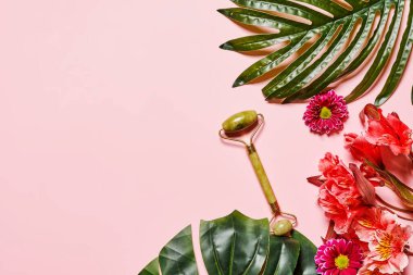 Pembe arkaplandaki tropikal yapraklar ve çiçekler - üstteki görünümde metin veya resminiz için boşluk