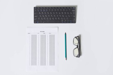 Masanın üstünde klavyesi, gözlüğü ve kalemi olan bir ofis masası.