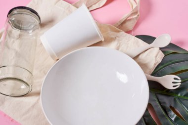 Beyaz bir tabak ve yanında da pembe bir kabın içinde bitki olan bazı fındıklar.