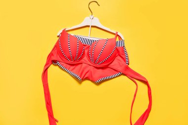 Askıda kırmızı bir bikini, sarı bir zemin ve sağ altta kopya alanı var.