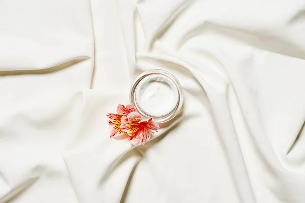 stock image a wedding ring and flower on a white satin fabric, shot from above with shallow focus in the eyepiece