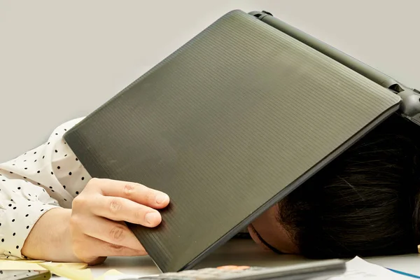 a person laying down with their head on top of an open laptop computer and papers scattered around them in the background